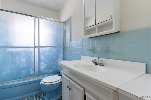 bathroom with toilet, enclosed tub / shower combo, vanity, and tile walls