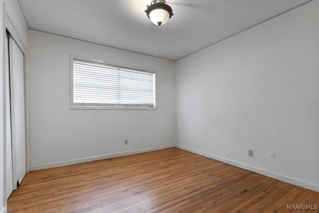 unfurnished bedroom with light wood finished floors, a closet, and baseboards