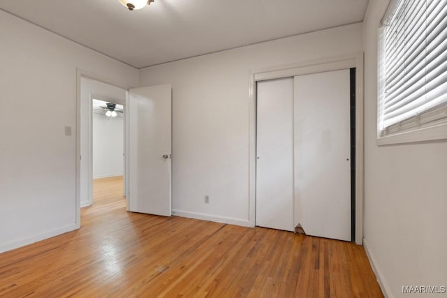 unfurnished bedroom with a closet, light wood-type flooring, and baseboards