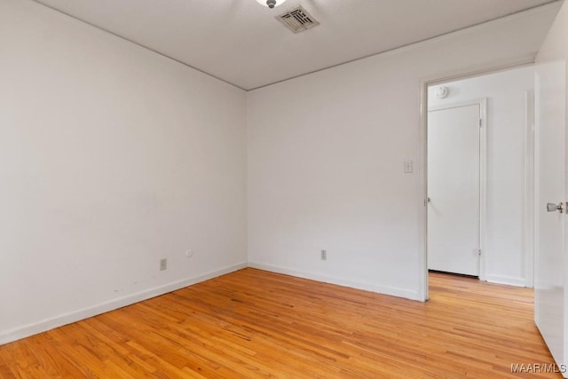 unfurnished room with light wood-type flooring, visible vents, and baseboards