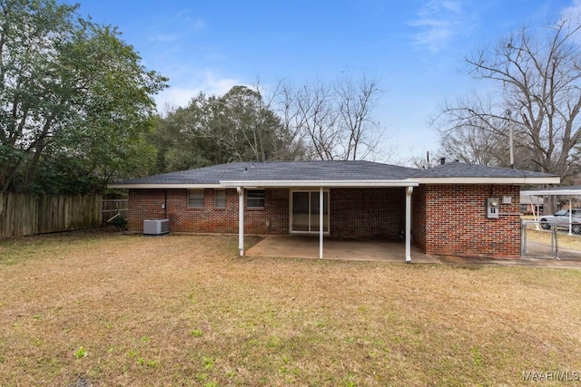 back of property featuring brick siding, fence, and a yard