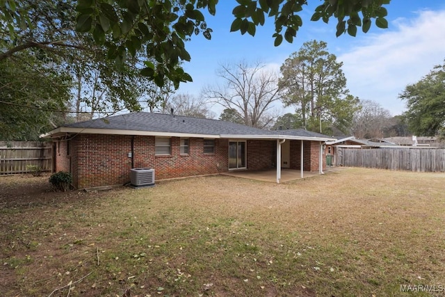 rear view of house with a fenced backyard, a lawn, a patio, and brick siding