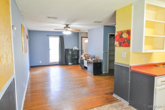 kitchen with baseboards, visible vents, white cabinets, ceiling fan, and wood finished floors