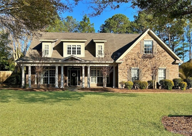 cape cod-style house featuring covered porch, a shingled roof, and a front lawn