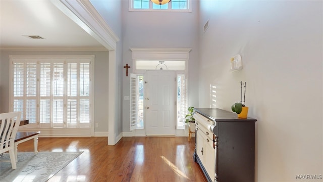 entryway with ornamental molding, a healthy amount of sunlight, visible vents, and wood finished floors