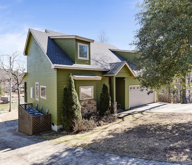 view of front of house with driveway, a shingled roof, an attached garage, and stone siding