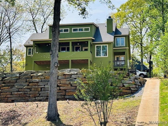 rear view of house with a shingled roof and a chimney