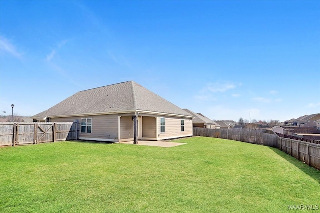 back of house with a shingled roof, a lawn, a patio area, and a fenced backyard