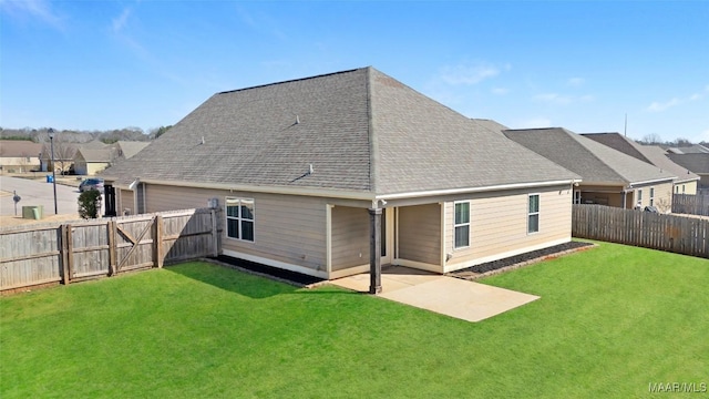 rear view of house with a fenced backyard, a shingled roof, and a lawn