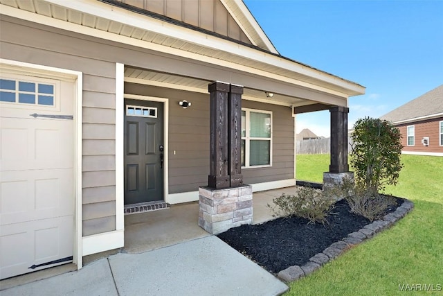 doorway to property featuring a garage, a lawn, a porch, and board and batten siding