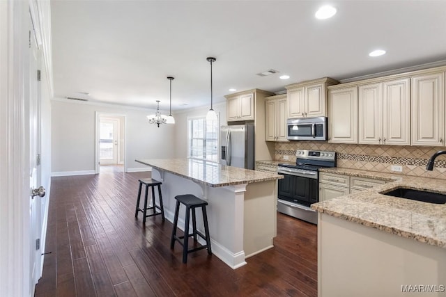 kitchen with a breakfast bar, cream cabinetry, visible vents, appliances with stainless steel finishes, and a sink