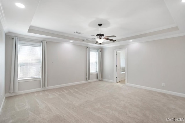 unfurnished room with light carpet, visible vents, baseboards, ornamental molding, and a tray ceiling