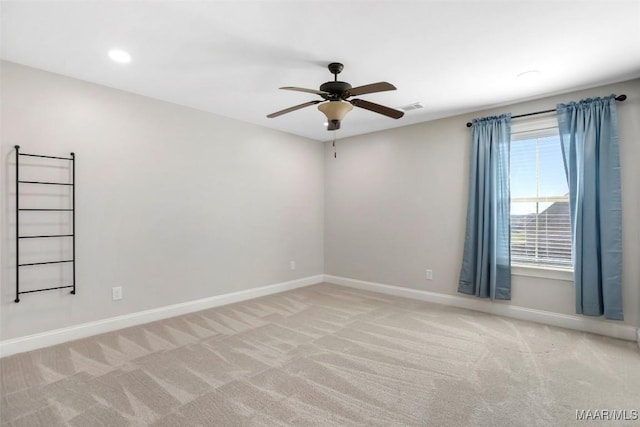 empty room featuring light carpet, a ceiling fan, visible vents, and baseboards