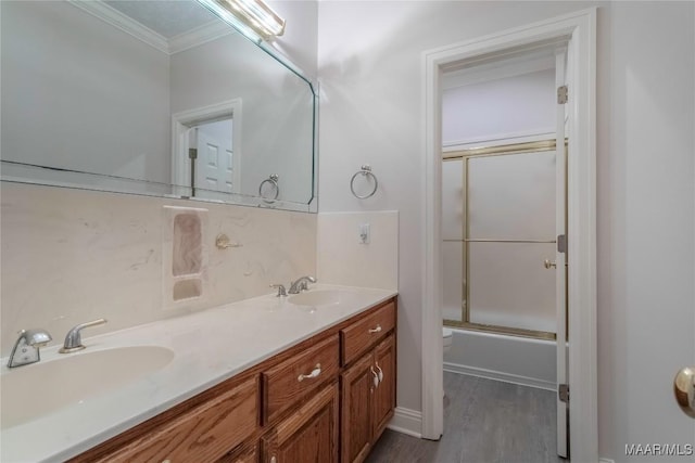 full bath featuring double vanity, toilet, ornamental molding, a sink, and wood finished floors