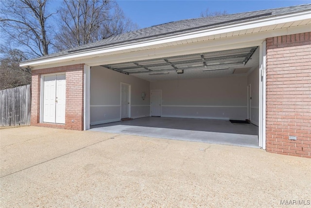 garage featuring concrete driveway and fence