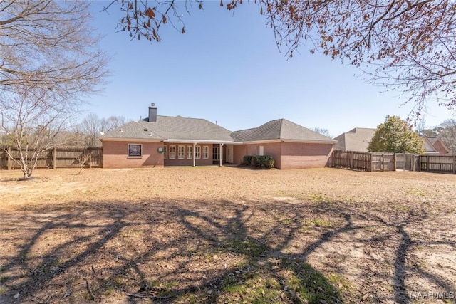 back of property with brick siding, a chimney, and a fenced backyard