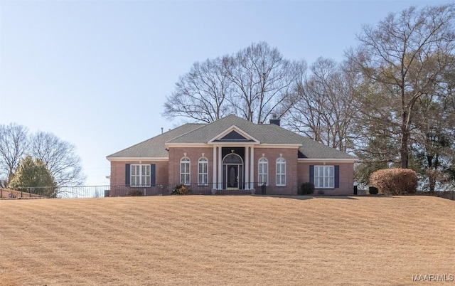 greek revival inspired property with a front yard, roof with shingles, and a chimney