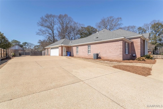 view of home's exterior with driveway, an attached garage, fence, and central AC