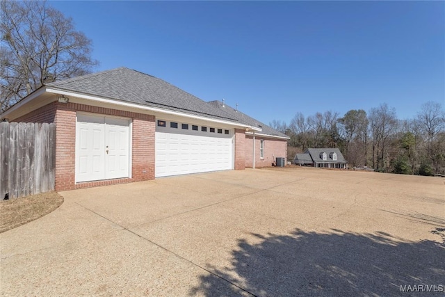 view of property exterior featuring a garage, brick siding, a shingled roof, fence, and concrete driveway