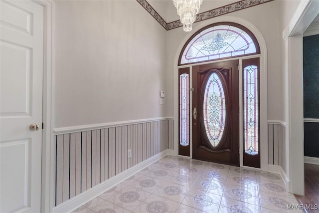 foyer entrance featuring a notable chandelier and wainscoting