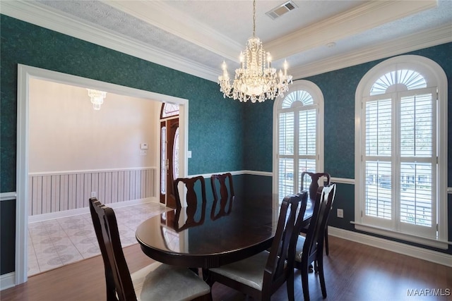 dining space with a wainscoted wall, visible vents, a notable chandelier, and wood finished floors