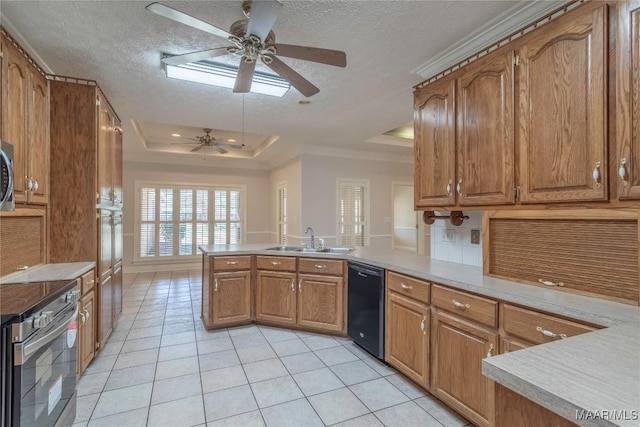 kitchen featuring stainless steel appliances, a peninsula, a sink, brown cabinetry, and a raised ceiling