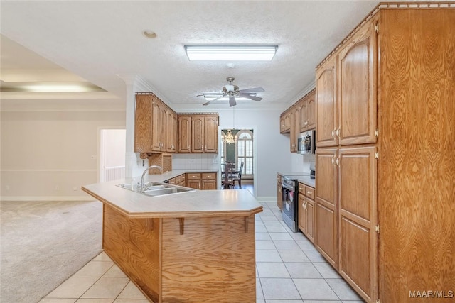 kitchen featuring light tile patterned floors, a peninsula, a sink, electric range oven, and stainless steel microwave