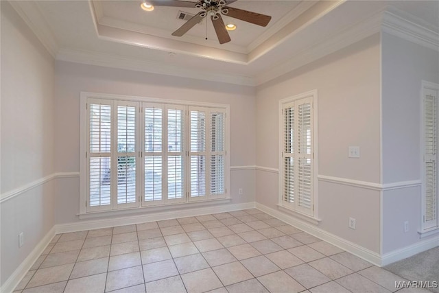 empty room with ornamental molding, a tray ceiling, a ceiling fan, and a healthy amount of sunlight