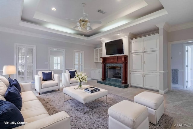 living area featuring crown molding, a raised ceiling, visible vents, a high end fireplace, and light carpet