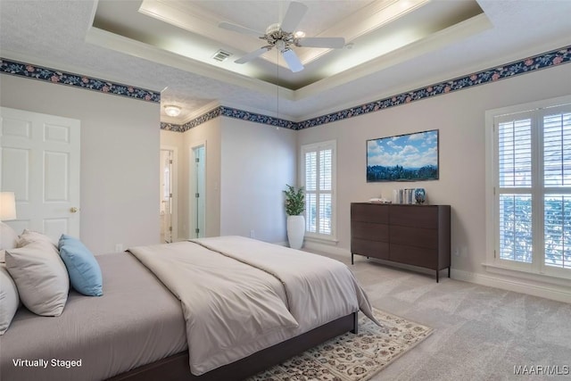 bedroom featuring visible vents, multiple windows, a tray ceiling, and light colored carpet