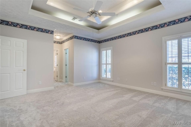 unfurnished room with carpet flooring, visible vents, baseboards, a raised ceiling, and crown molding