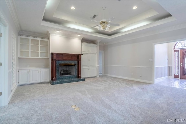 unfurnished living room with light carpet, a tray ceiling, a premium fireplace, and crown molding