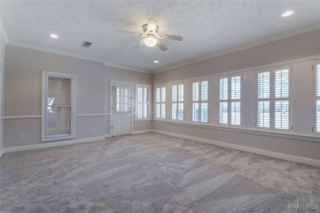 carpeted empty room with baseboards, a textured ceiling, visible vents, and crown molding