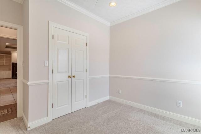 unfurnished bedroom with baseboards, carpet, ornamental molding, and a closet