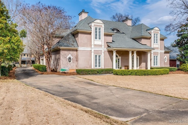 view of front of property with driveway, a chimney, and stucco siding