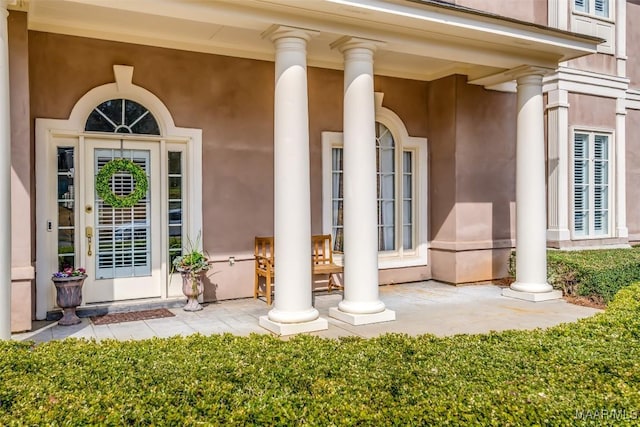 property entrance featuring a porch and stucco siding