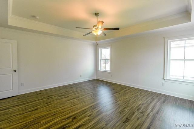 unfurnished room featuring ornamental molding, a raised ceiling, dark wood finished floors, and baseboards