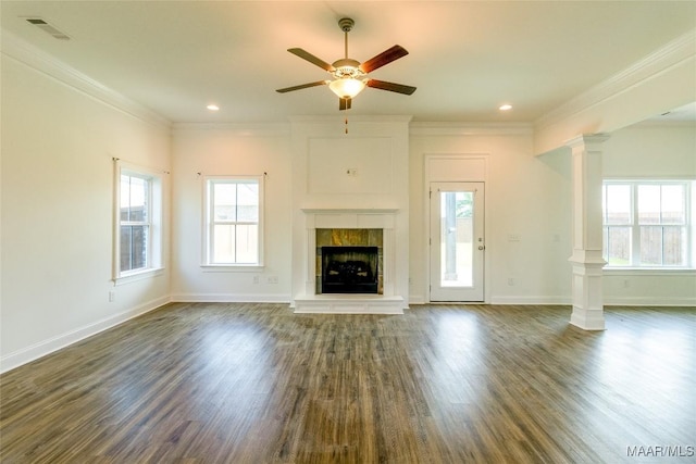 unfurnished living room with a tile fireplace, visible vents, ornamental molding, dark wood-style floors, and decorative columns