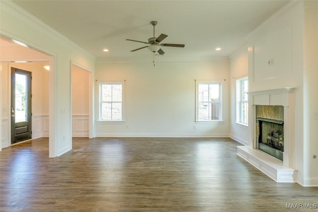 unfurnished living room featuring a wealth of natural light, a fireplace with raised hearth, and crown molding