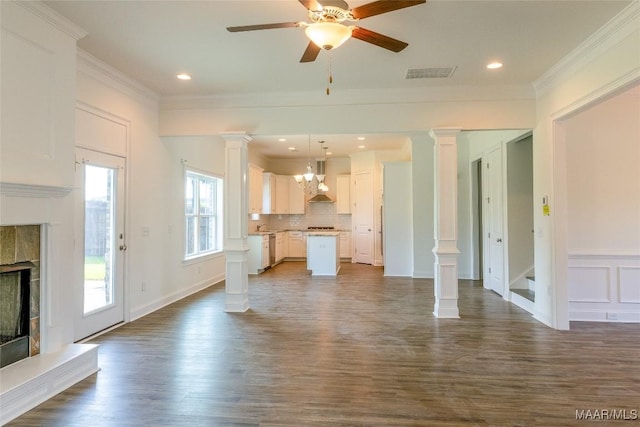 unfurnished living room featuring crown molding, a tile fireplace, visible vents, and ornate columns