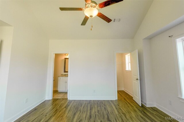 unfurnished bedroom featuring baseboards, wood finished floors, visible vents, and a walk in closet