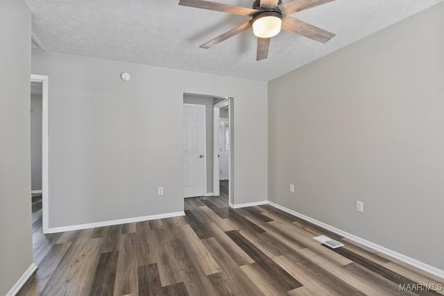 empty room with a textured ceiling, ceiling fan, wood finished floors, visible vents, and baseboards