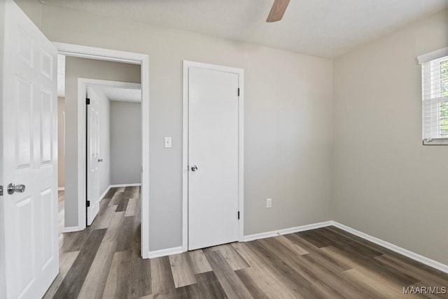 unfurnished bedroom featuring dark wood-style floors, ceiling fan, and baseboards