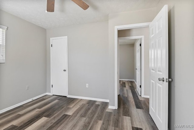 unfurnished bedroom featuring a ceiling fan, a textured ceiling, baseboards, and dark wood-style flooring