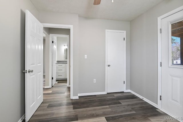 unfurnished bedroom featuring a textured ceiling, dark wood-style flooring, and baseboards