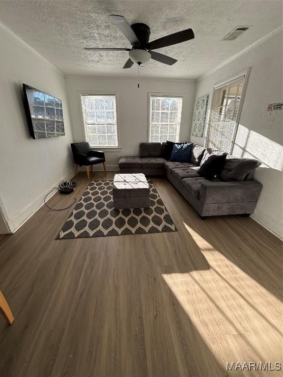 living room with visible vents, a textured ceiling, and wood finished floors