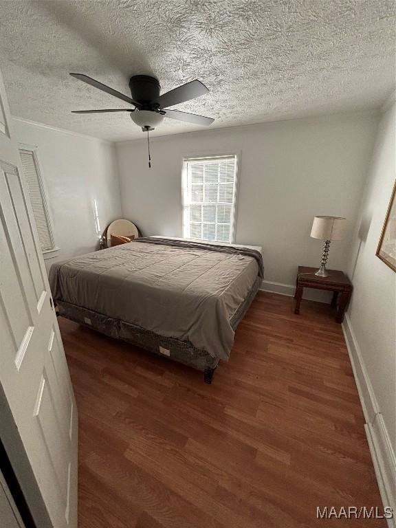 bedroom featuring baseboards, a textured ceiling, a ceiling fan, and wood finished floors