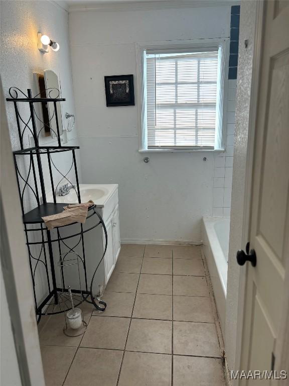 bathroom featuring tile patterned flooring, vanity, baseboards, and a bath