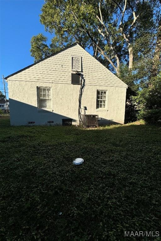 view of side of home with central air condition unit, stucco siding, and a yard