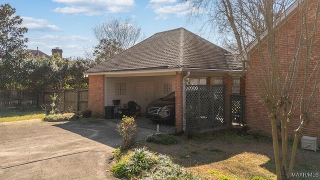 view of side of home featuring brick siding, fence, and driveway